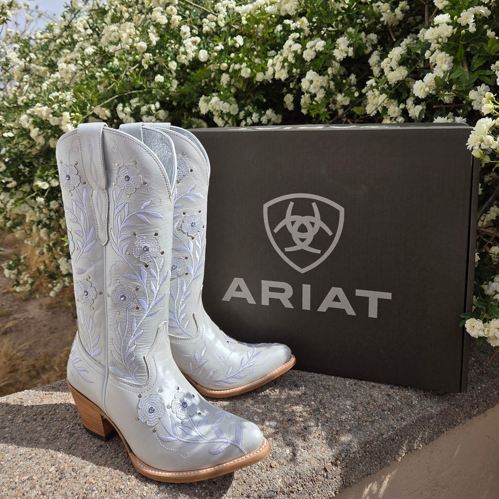 A pair of Women’s Leather Boots "Romance" by Ariat (10061310) in crisp white full-grain leather, featuring delicate floral stitching on the mid-calf shaft, a snip toe, and a 1.5-inch riding heel. Designed with Ariat’s 4LR™ technology for comfort and a Duratread™ sole for traction, these boots embody Western elegance for the modern cowgirl. 

