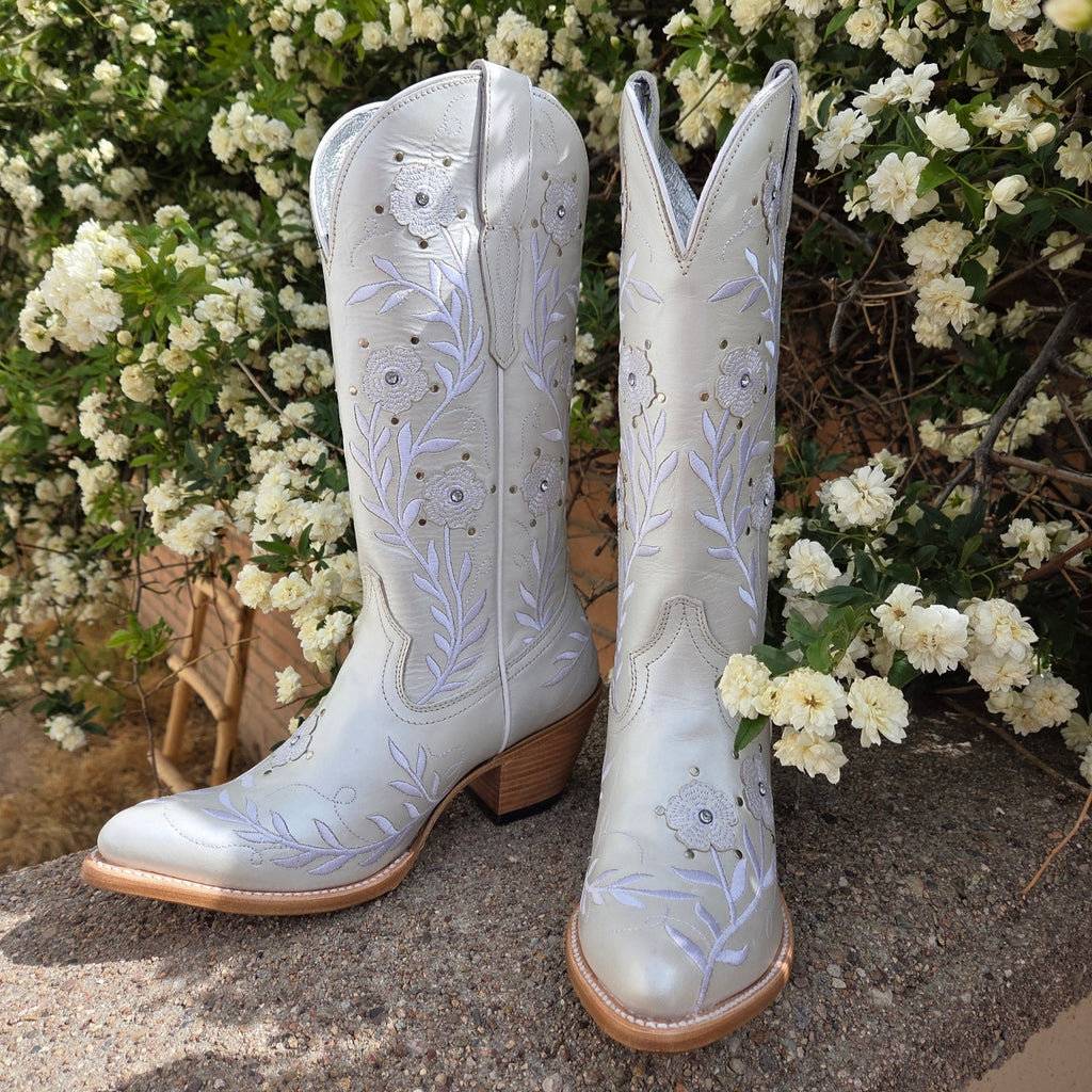 A pair of Women’s Leather Boots "Romance" by Ariat (10061310) in crisp white full-grain leather, featuring delicate floral stitching on the mid-calf shaft, a snip toe, and a 1.5-inch riding heel. Designed with Ariat’s 4LR™ technology for comfort and a Duratread™ sole for traction, these boots embody Western elegance for the modern cowgirl. 

