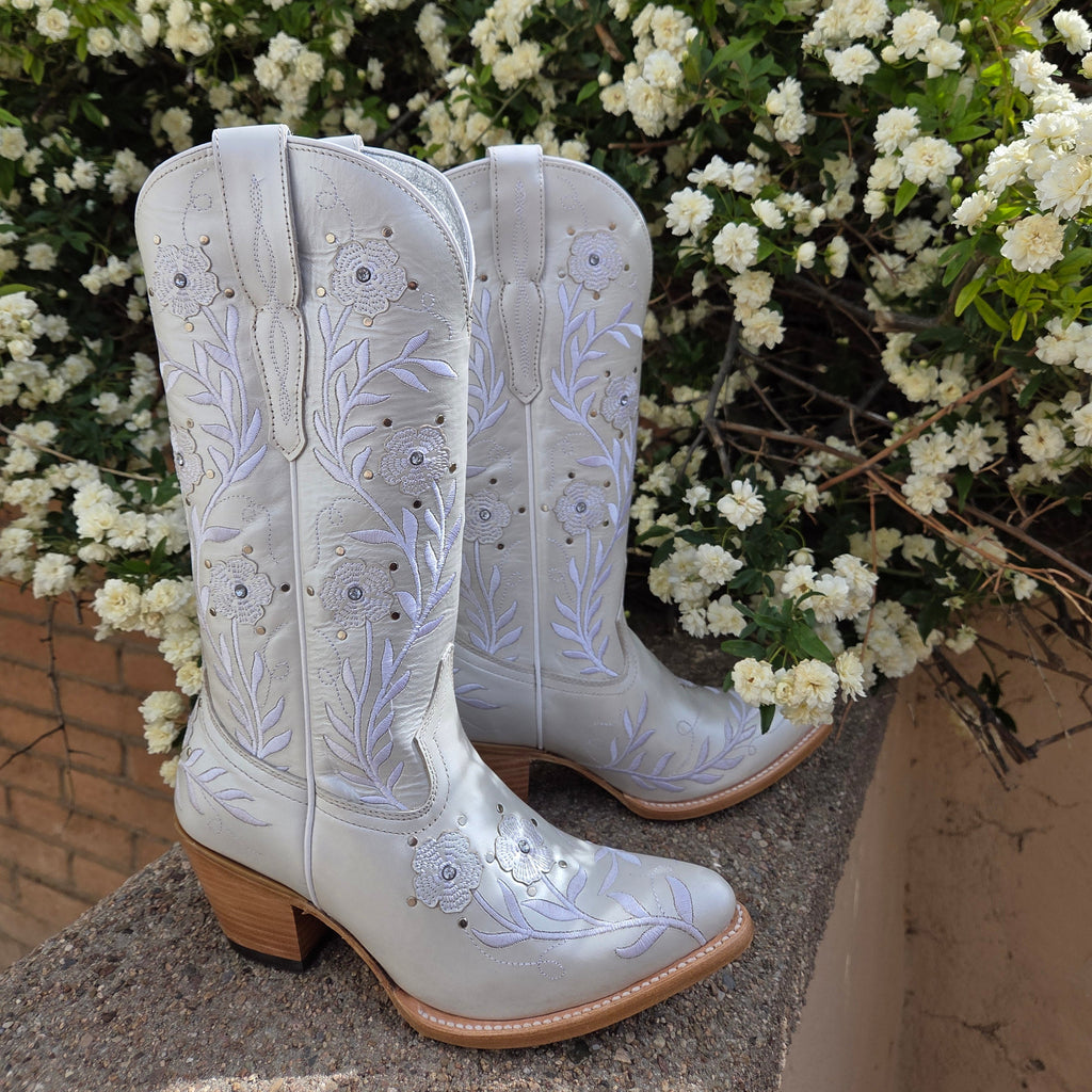 A pair of Women’s Leather Boots "Romance" by Ariat (10061310) in crisp white full-grain leather, featuring delicate floral stitching on the mid-calf shaft, a snip toe, and a 1.5-inch riding heel. Designed with Ariat’s 4LR™ technology for comfort and a Duratread™ sole for traction, these boots embody Western elegance for the modern cowgirl. 

