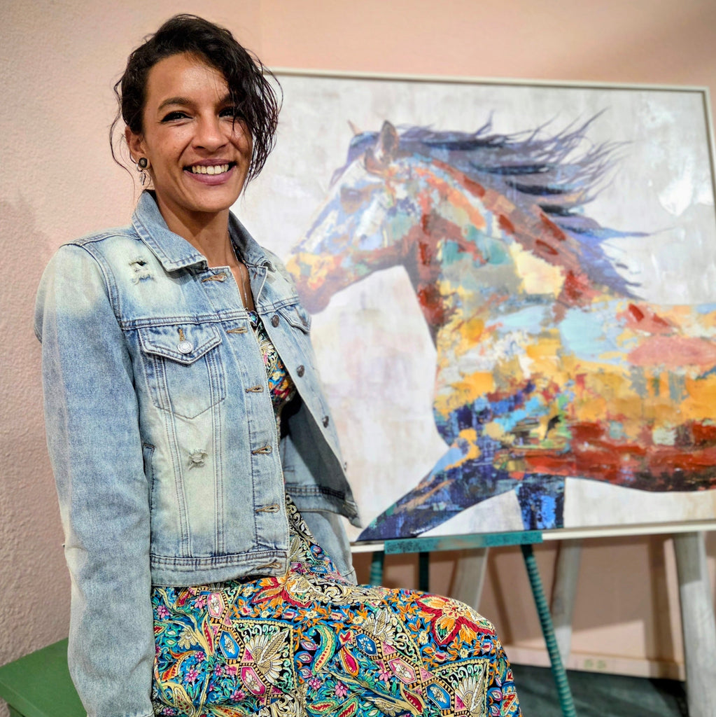 Stylish woman posing on a dusty street in historic Tombstone, Arizona, wearing a distressed light blue denim jacket featuring a vibrant bedazzled cowgirl boots design on the back by Forward Design