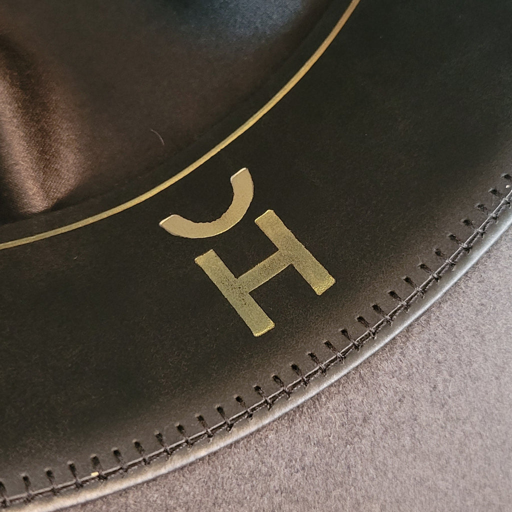 Cattle brand is found in gold on the sweatband.