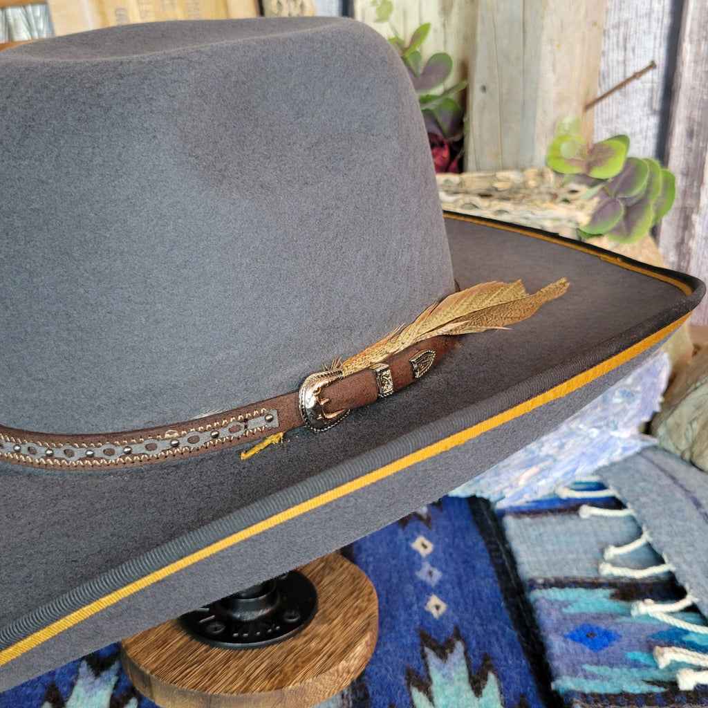 A close-up of the brown band buckle and feather accent.