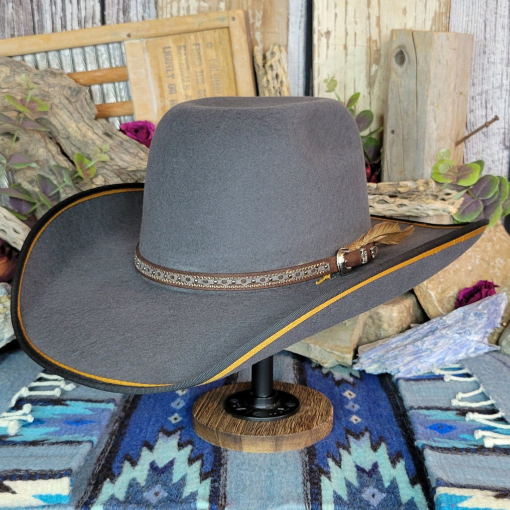 A gray wool felt hat with a detailed band, belt strap, and feather.