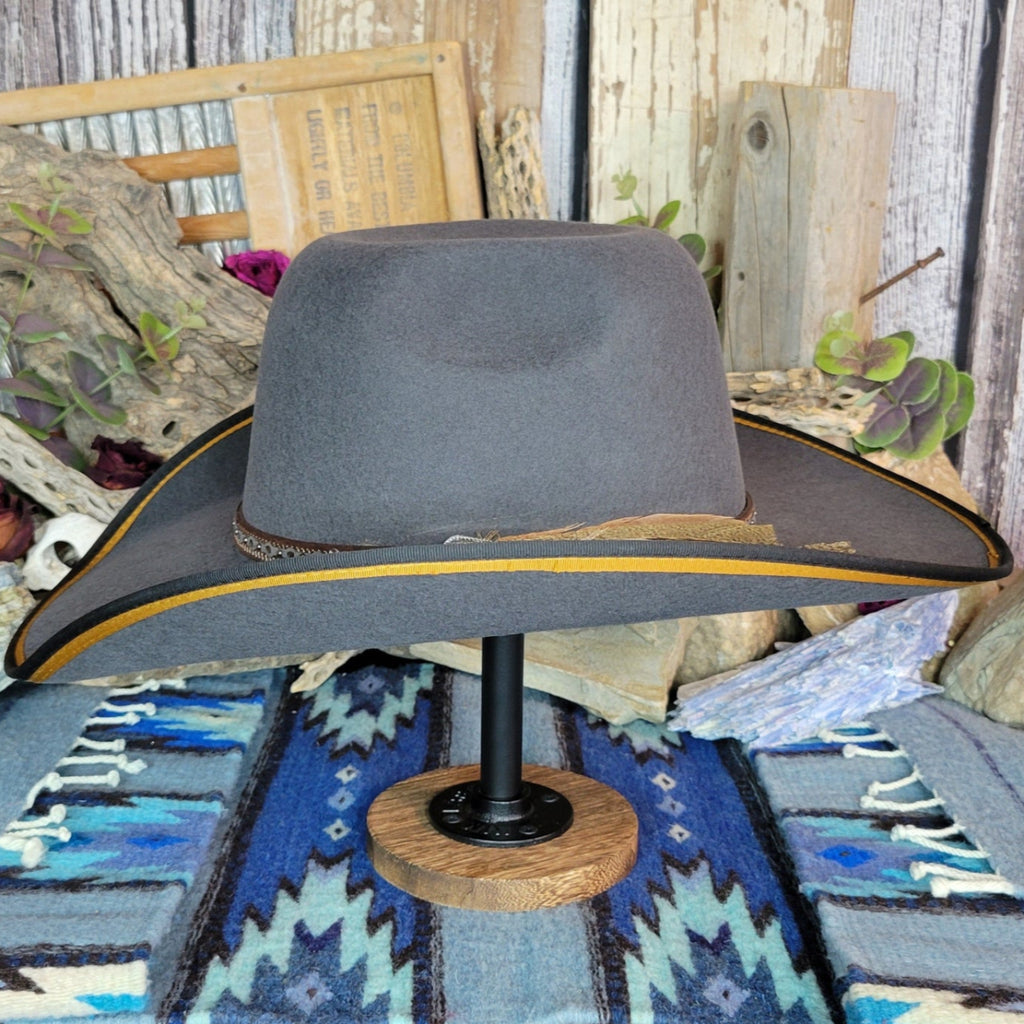 A gray wool felt hat with a detailed band, belt strap, and feather.