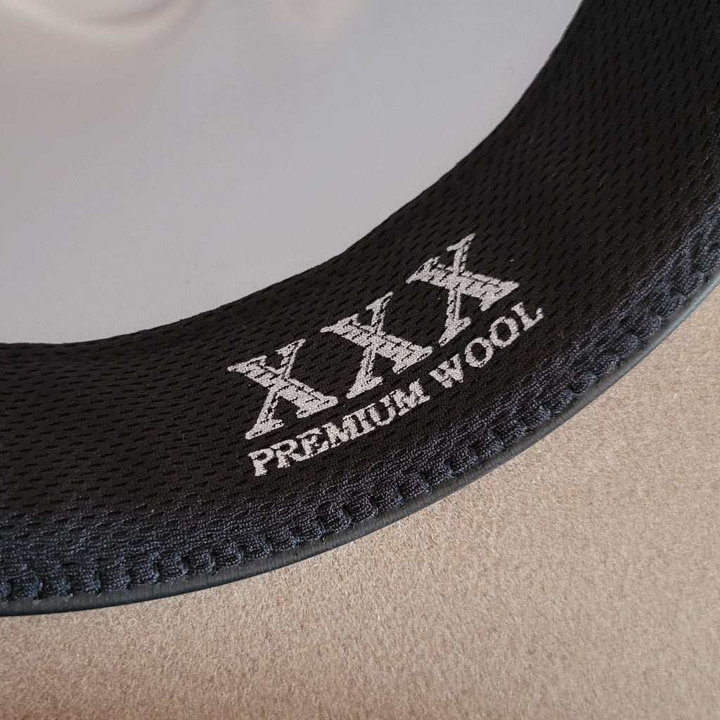 Close-up of a hat band with 'XXL Premium Wool' embroidery on the sweatband.