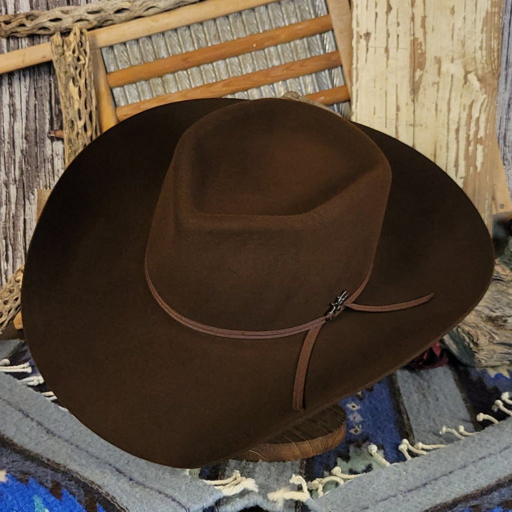 Brown wool cowboy hat with a brown band tied with a silver detail.