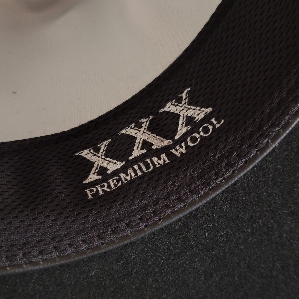 Close-up of a black hat with 'XXX Premium Wool' lettering on the sweatband.