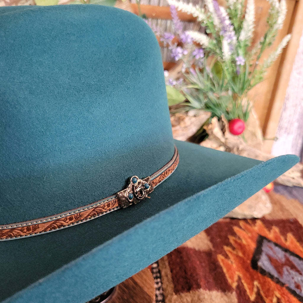 A close-up of the decorative leather hat band with turquoise stitching and silver detail.