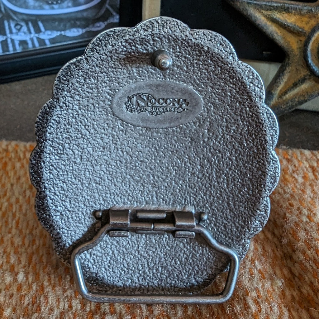 Back of the belt buckle featuring the rough surface and logo.