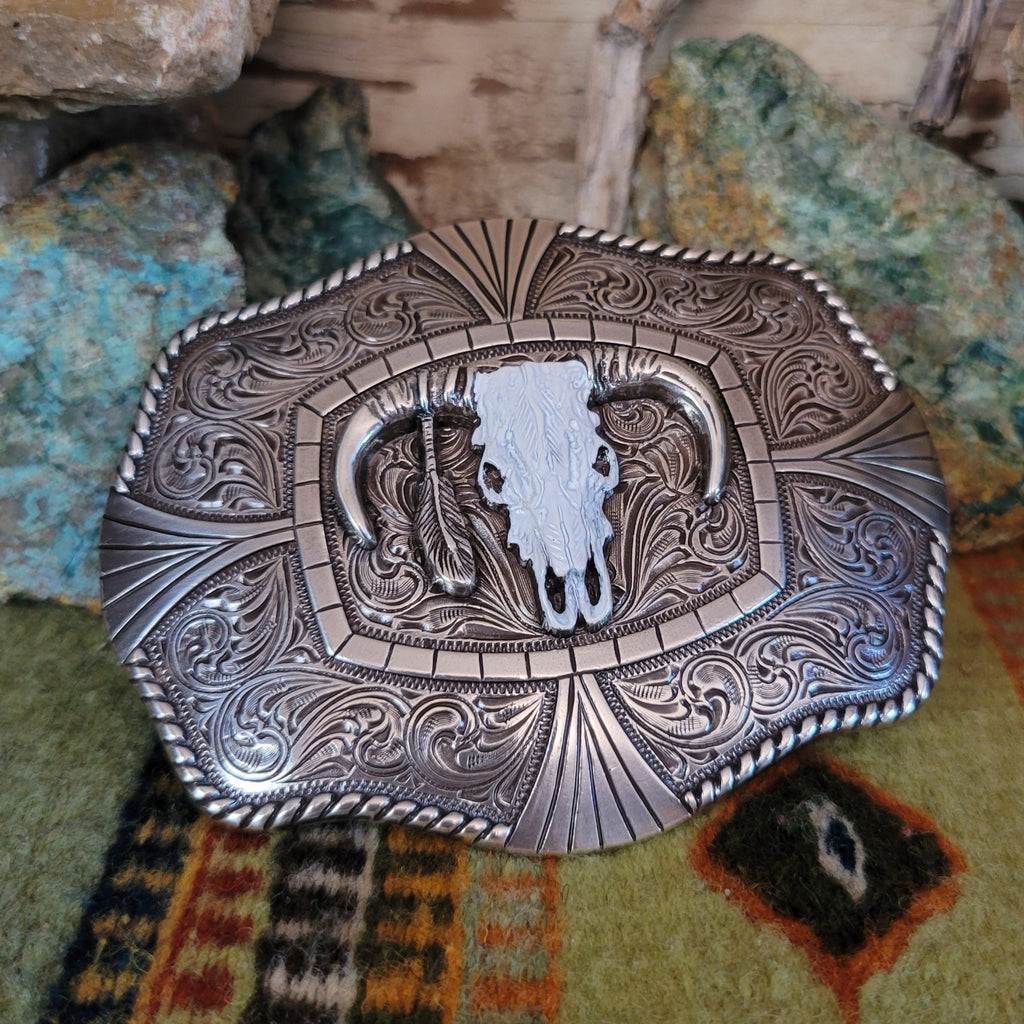 An ornately detailed buckle with a steer skull and twisted rope design.