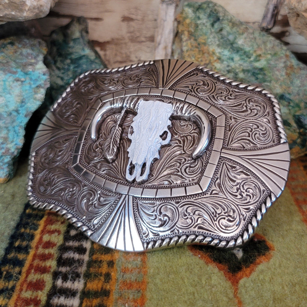 An ornately detailed buckle with a steer skull and twisted rope design.