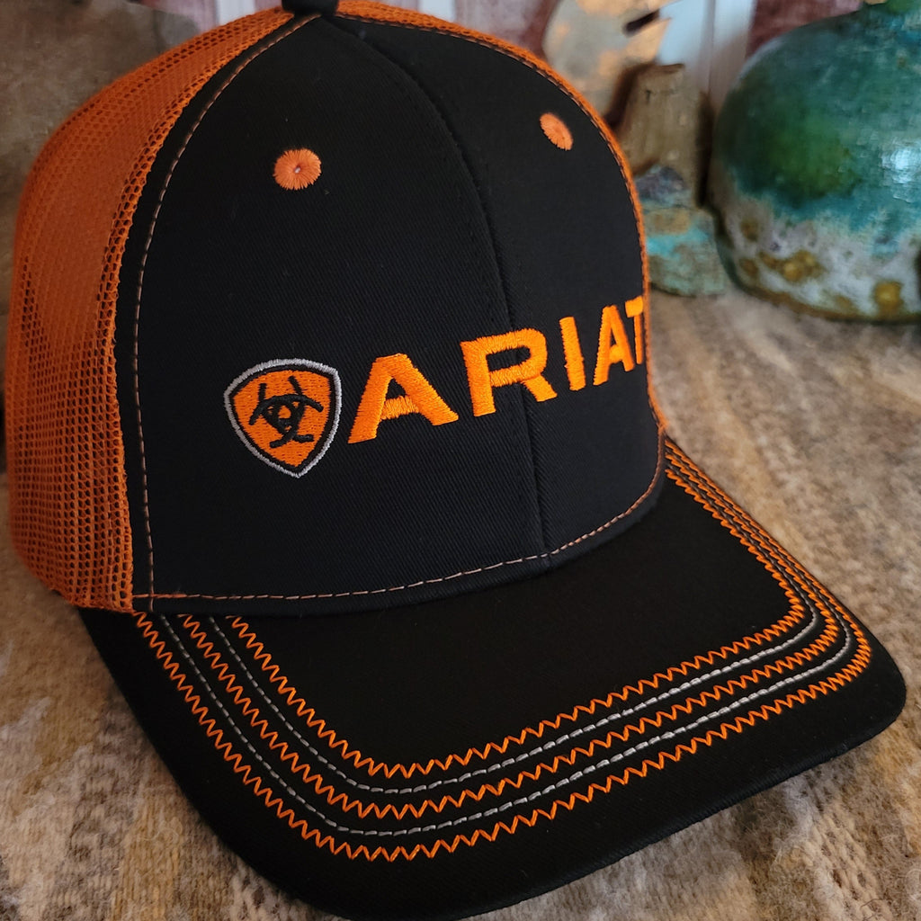 Close-up of orange Ariat logo with embroidered stitching on black front.