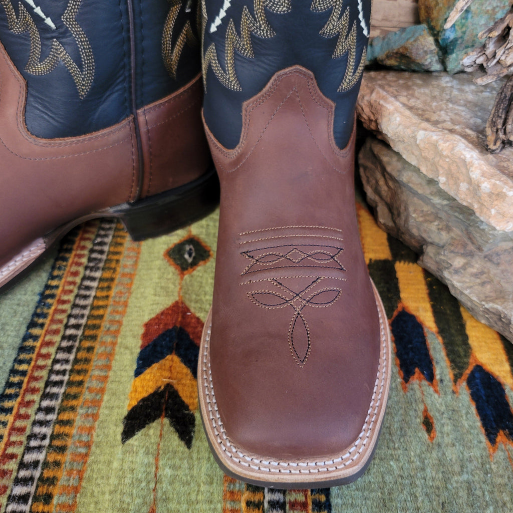 The brown square toe of the shoe showcases ornate stitching.