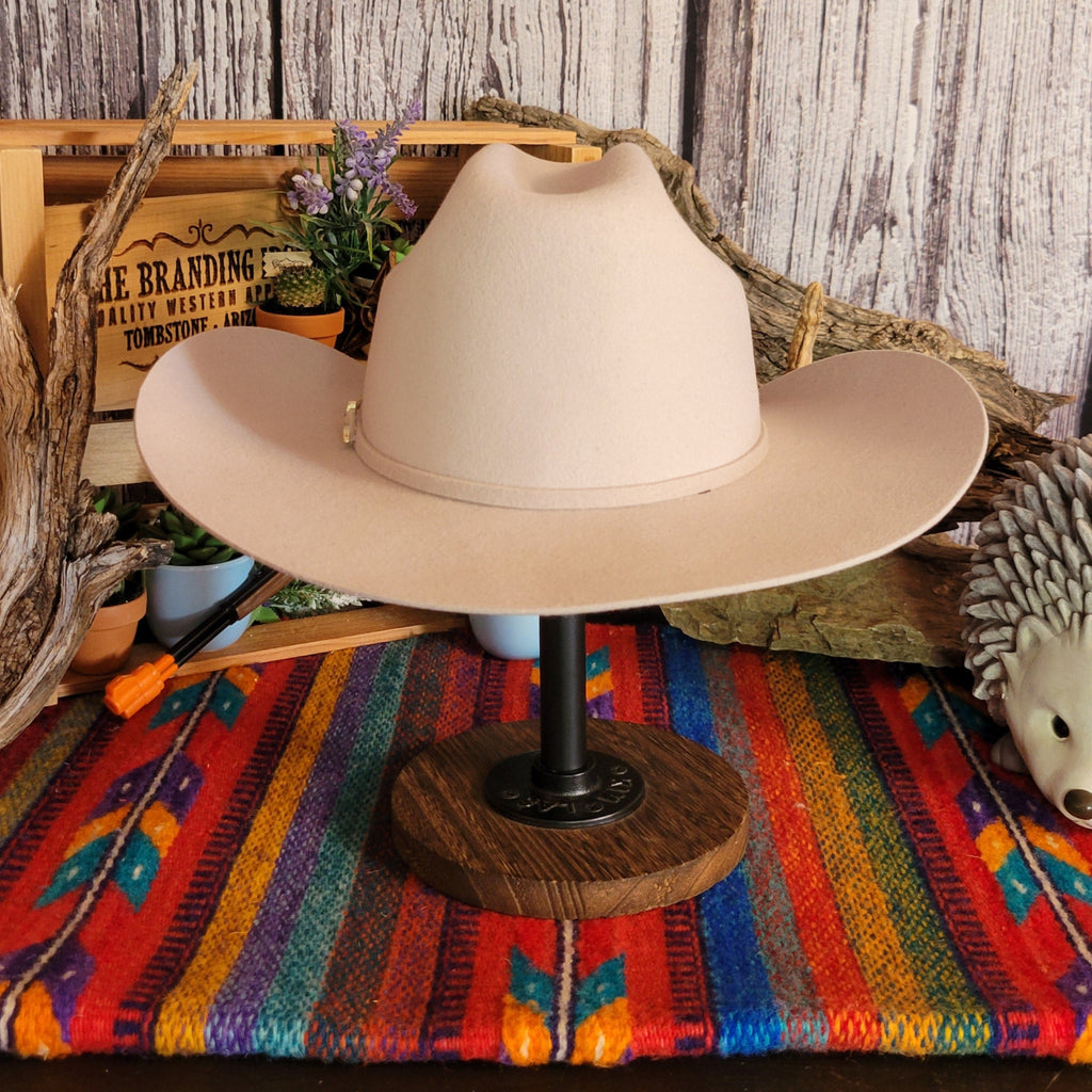 Cream colored wool hat with thin hat band and gold buckle detail.