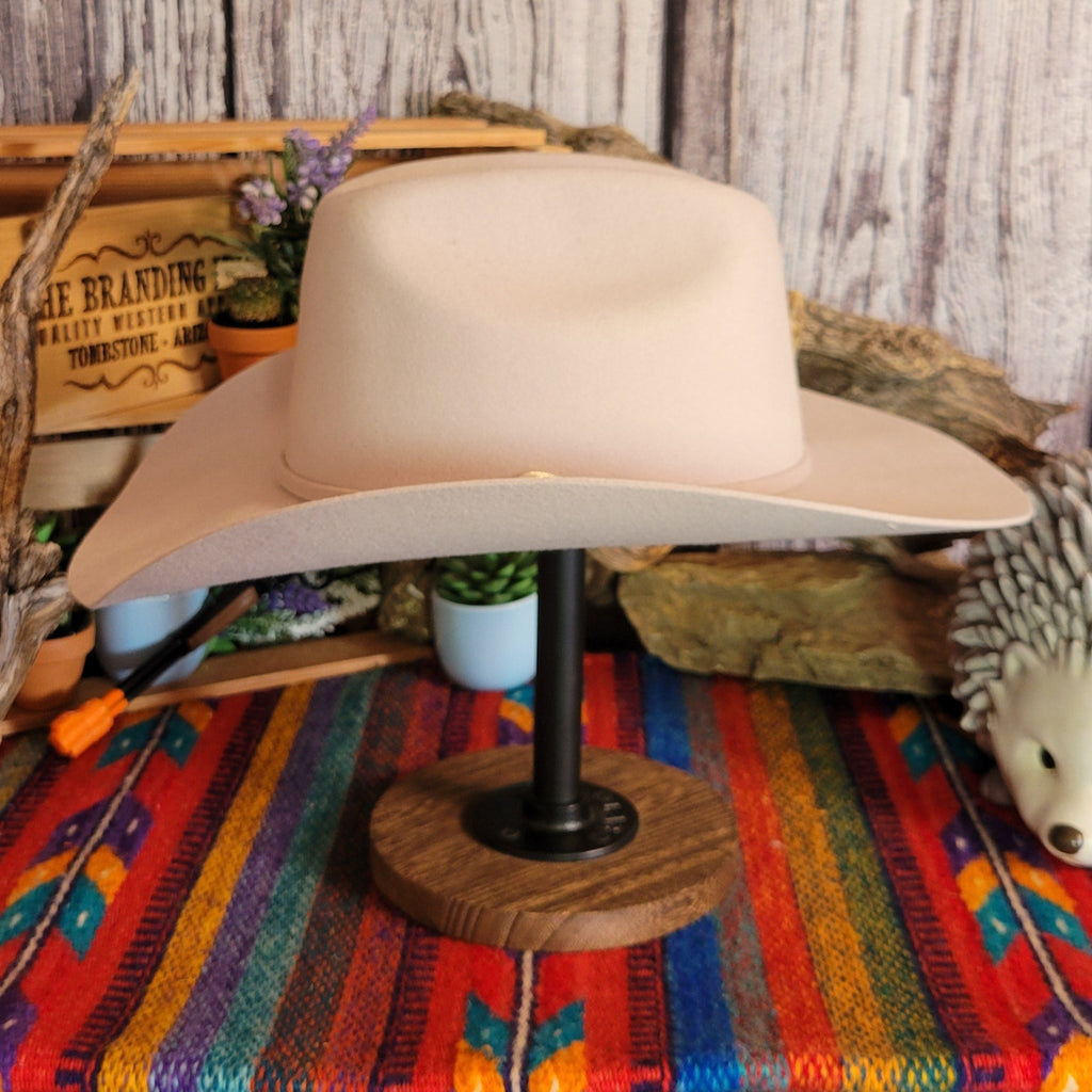 Cream colored wool hat with thin hat band and gold buckle detail.