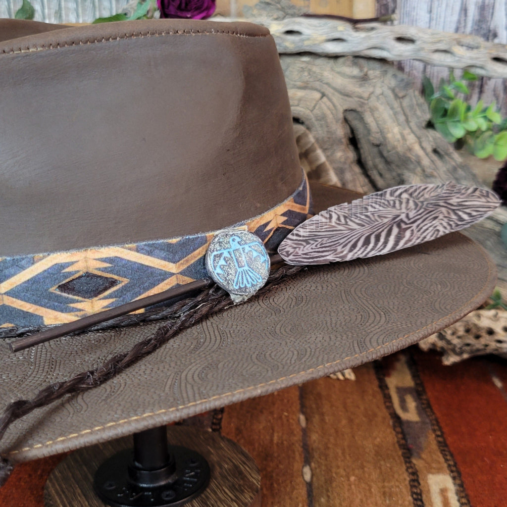 A close-up view of the turquoise Thunderbird concho, leather cords, and large accent piece on the band.