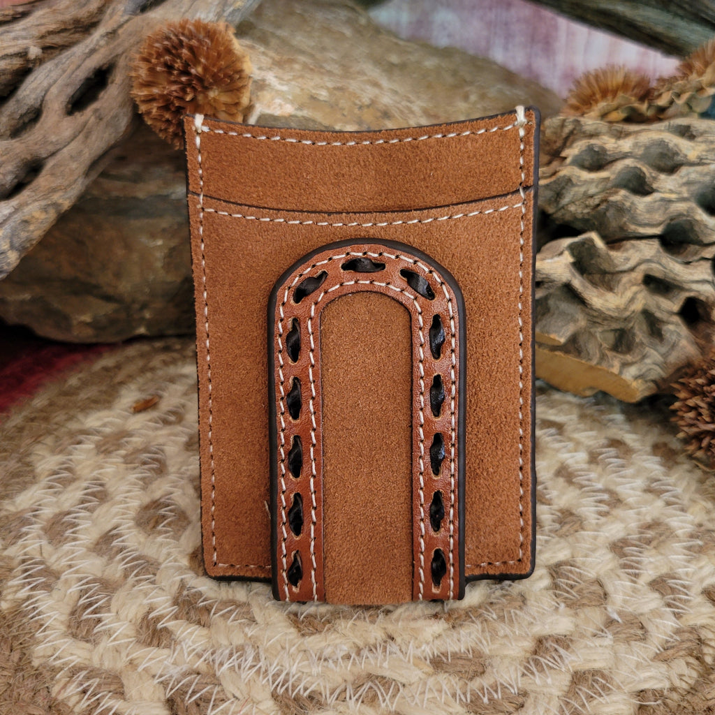 A tan suede Men's Money Clip Wallet by 3D Belt Company rests on a woven mat, surrounded by rustic driftwood and dried desert plants. The wallet showcases an arched cutout with black decorative stitching, highlighting its Western craftsmanship against a natural, earthy backdrop.