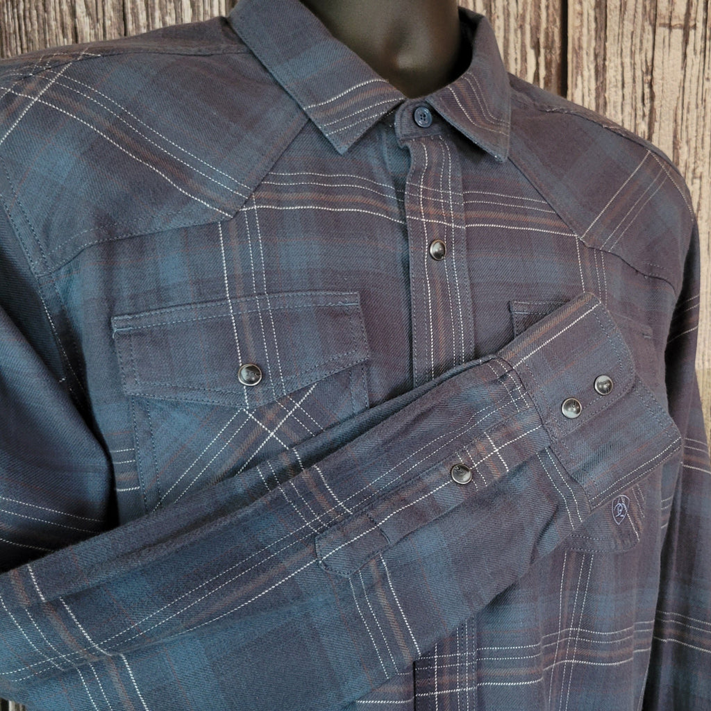 Blue plaid shirt with dual chest pockets and pearl snap closure.
