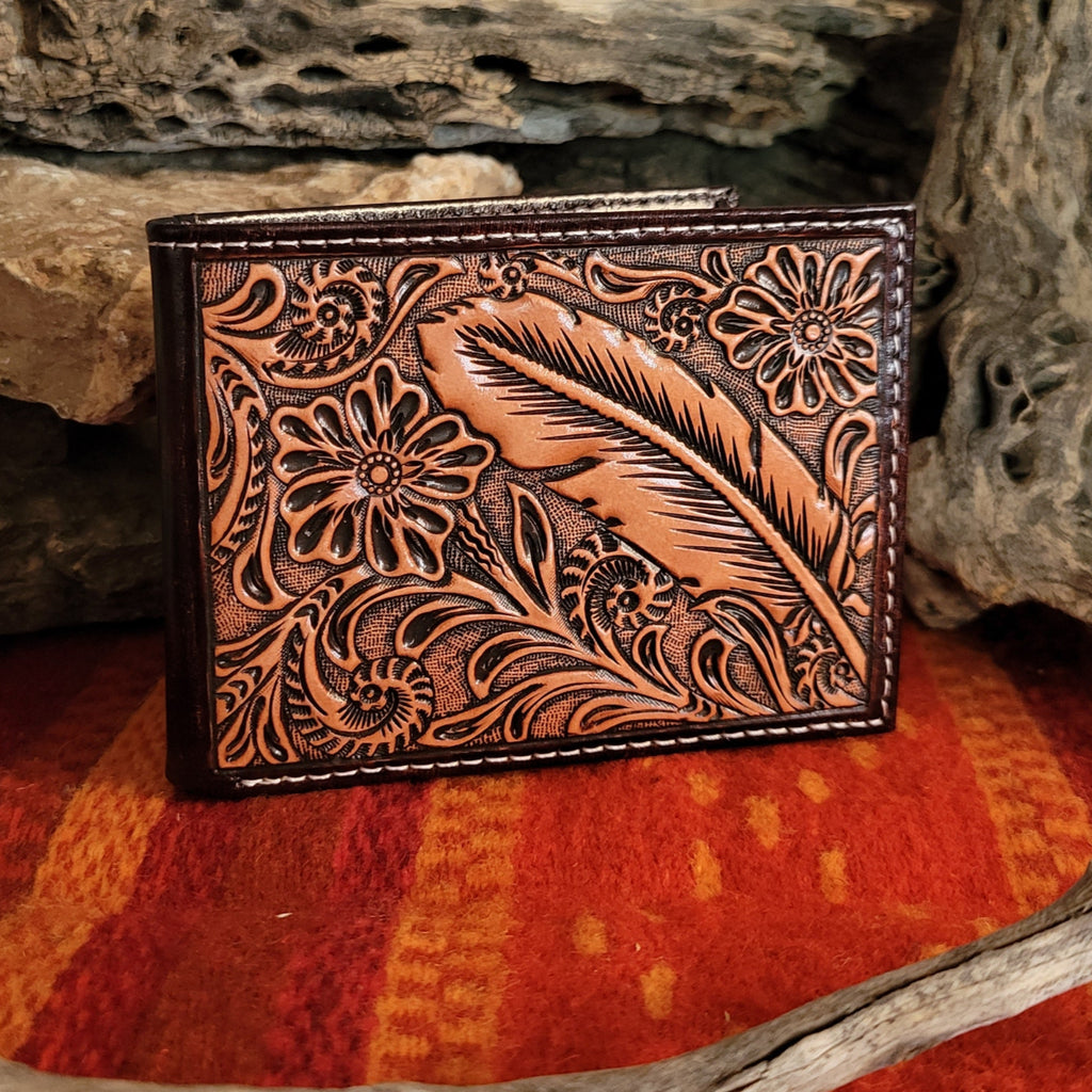 Tan leather wallet with tooled floral and feather patterns.