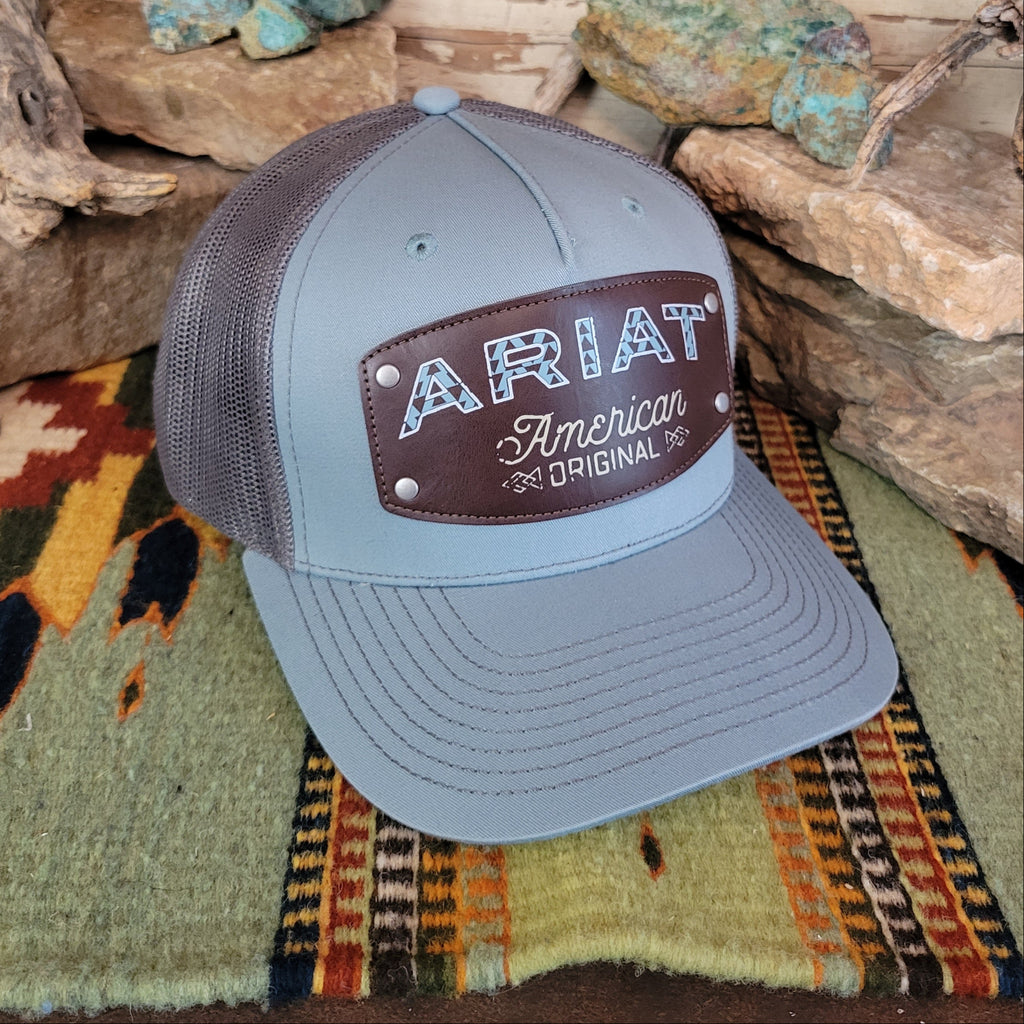 A light gray trucker cap with a brown leather patch.