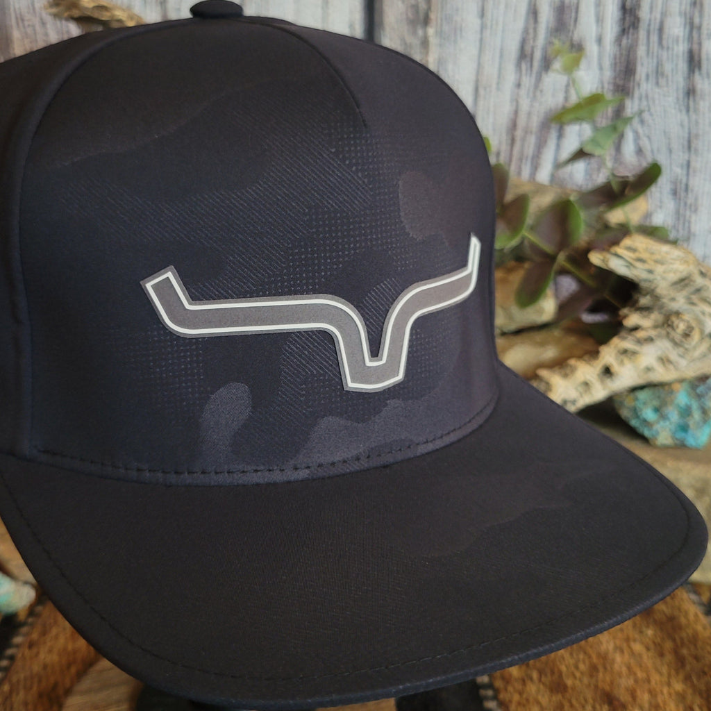 A close-up view of the Kimes Ranch logo on the front of the black camo cap.