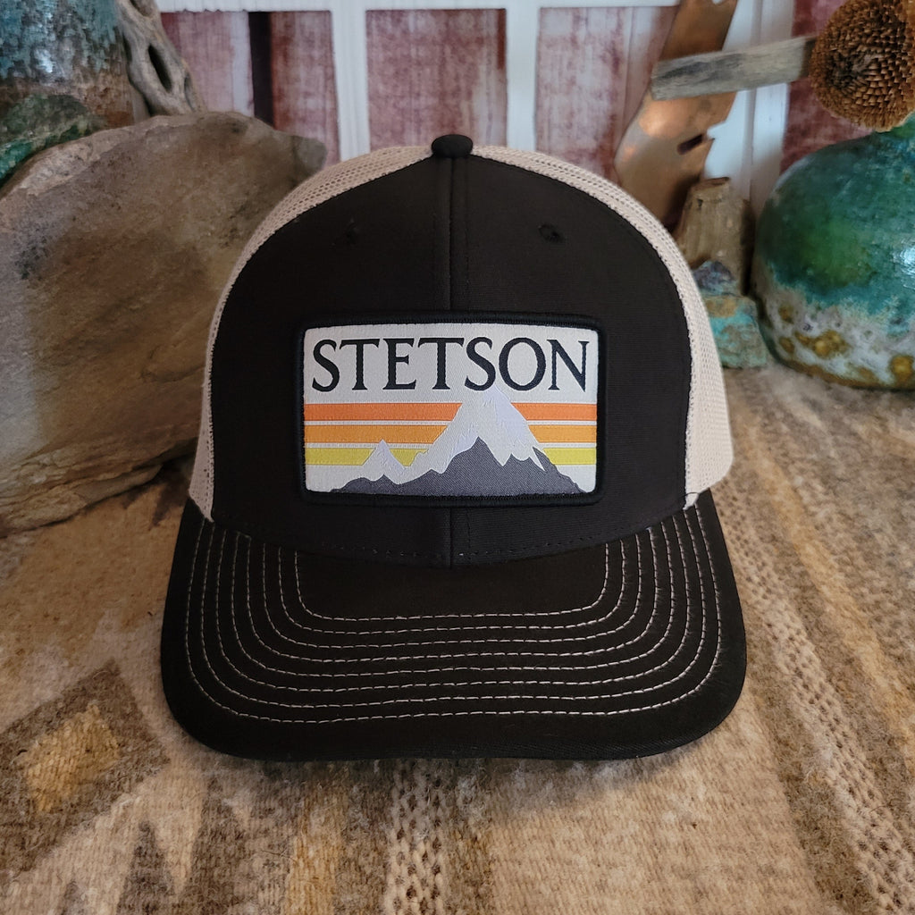 Black front with glacier mountain patch featuring orange and yellow stripes and Stetson branding.