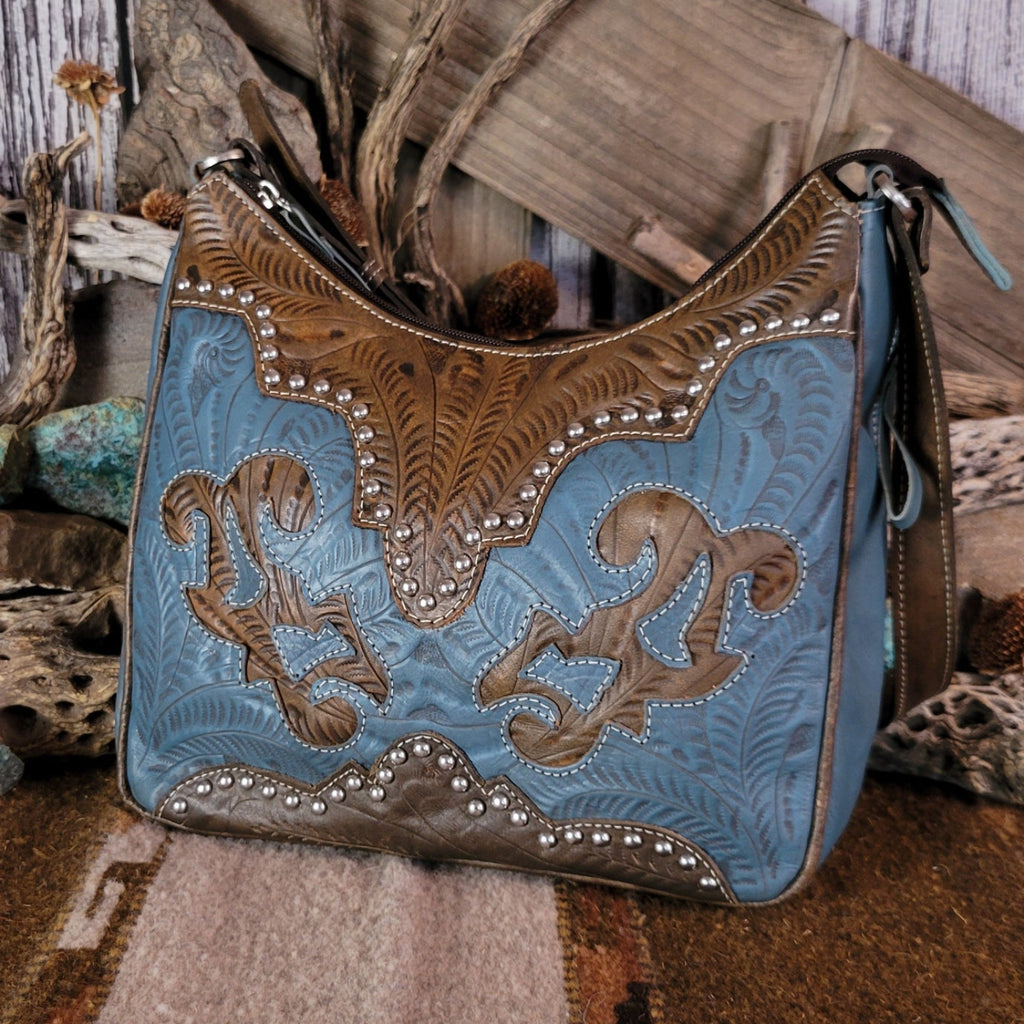 Leather tote bag with studded details, blue stain, and hand-tooled design.