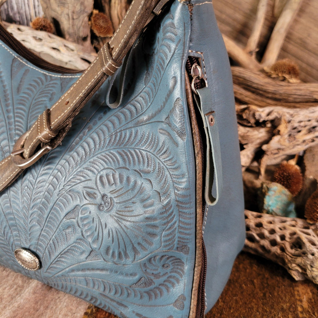 Leather tote bag with studded details, blue stain, and hand-tooled design.