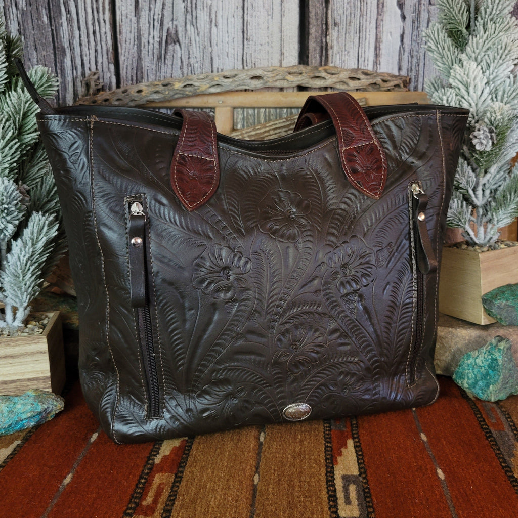 Hand-stained leather tote bag with floral hand-tooled designs and red and dark brown coloring.