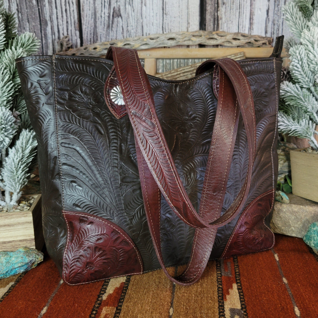 Hand-stained leather tote bag with floral hand-tooled designs and red and dark brown coloring.