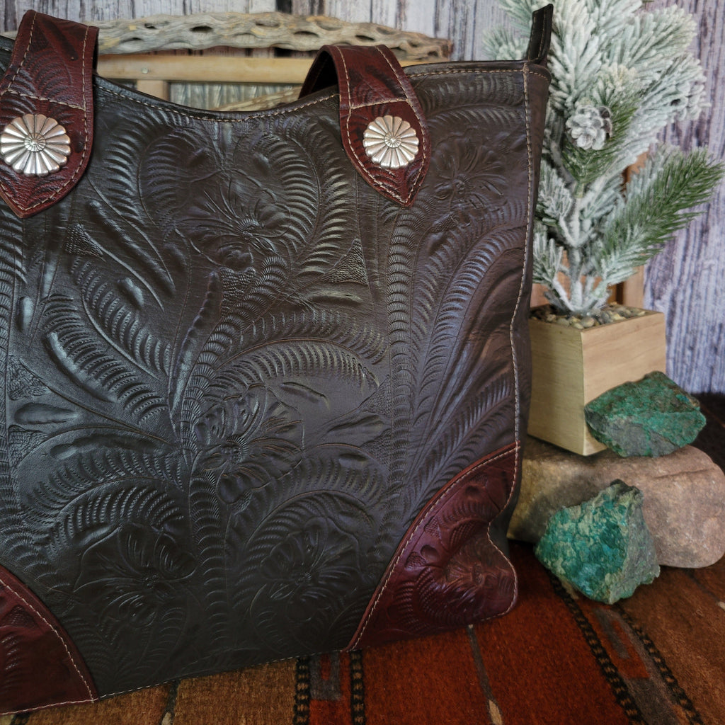 Hand-stained leather tote bag with floral hand-tooled designs and red and dark brown coloring.