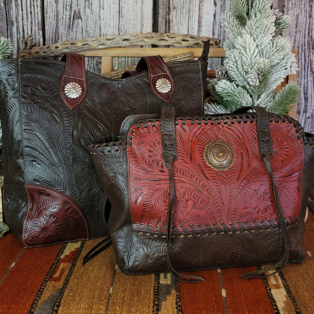 Hand-stained leather tote bag with floral hand-tooled designs and red and dark brown coloring with matching bag pictured.