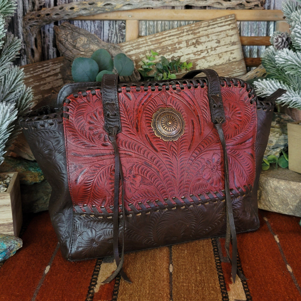 Hand-stained red and rich brown, tote has concealed carry pockets and hand-tooled floral designs.