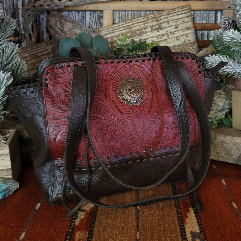 Hand-stained red and rich brown, tote has concealed carry pockets and hand-tooled floral designs.