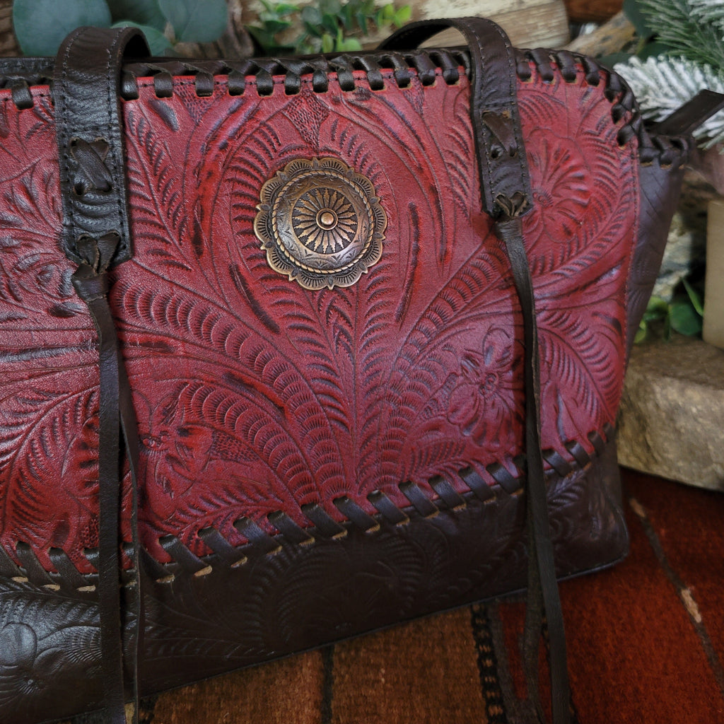 Hand-stained red and rich brown, tote has concealed carry pockets and hand-tooled floral designs.