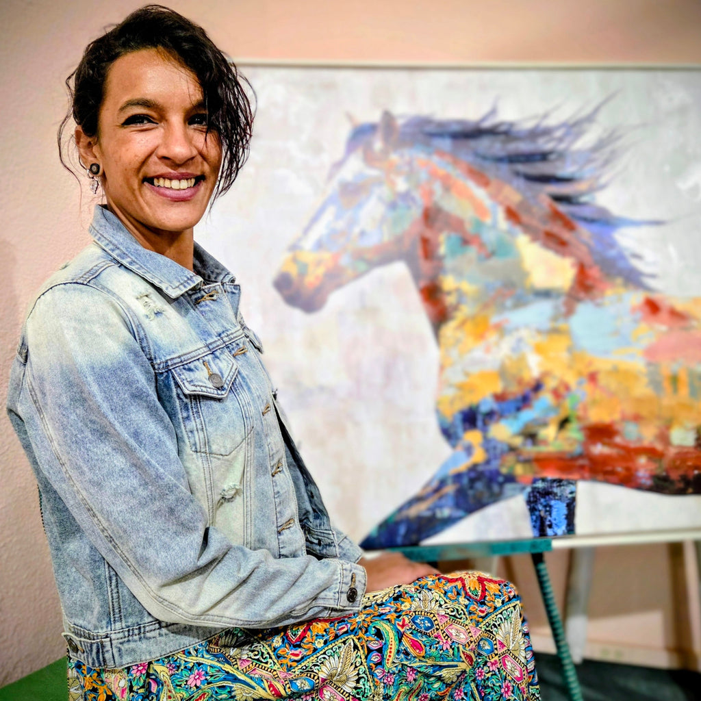 Stylish woman posing on a dusty street in historic Tombstone, Arizona, wearing a distressed light blue denim jacket featuring a vibrant bedazzled cowgirl boots design on the back by Forward Design
