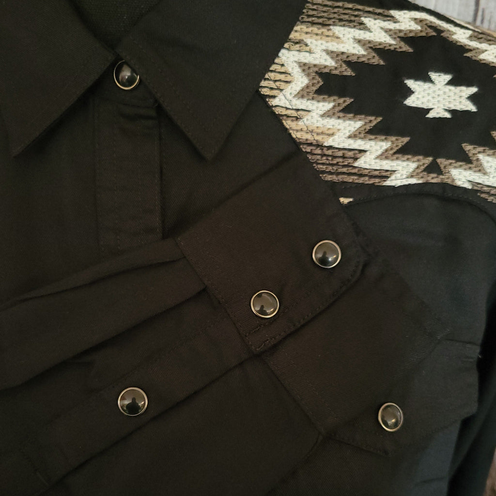 A close-up of the snap buttons and embroidery of the design.