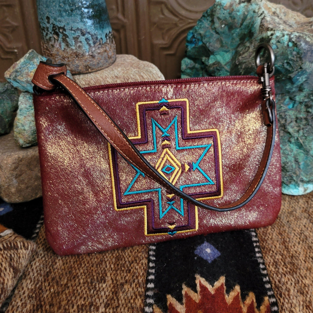 Embroidered clutch with leather accents, vibrant designs and strap.