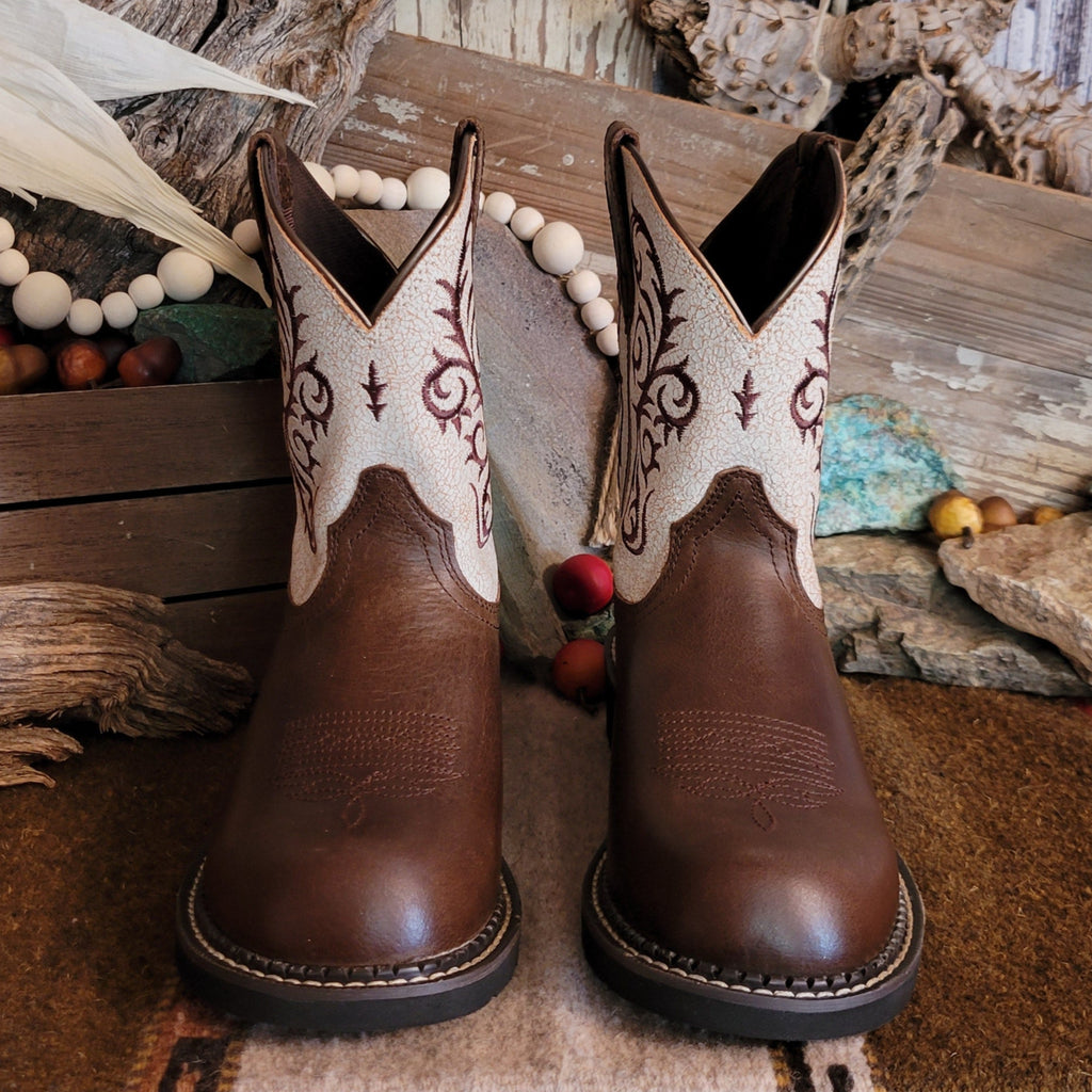 Brown cowgirl boot with dark brown toe and white shaft featuring intricate brown stitching.