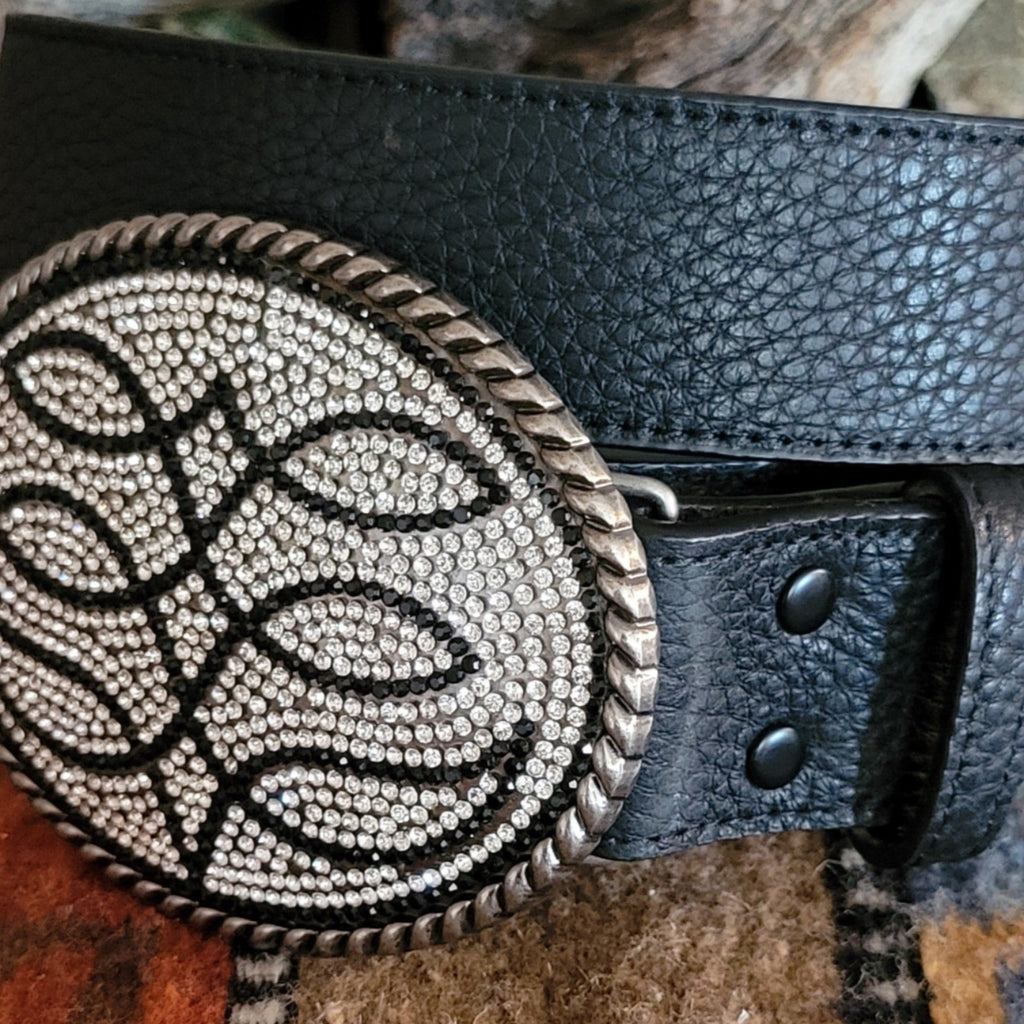 A close-up of the textures, black surface of the belt and rhinestone buckle.