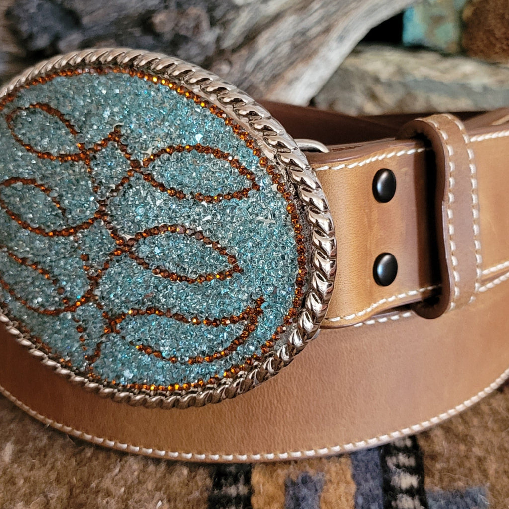 A close-up of the smooth brown leather of the belt and turquoise and brown rhinestone buckle.