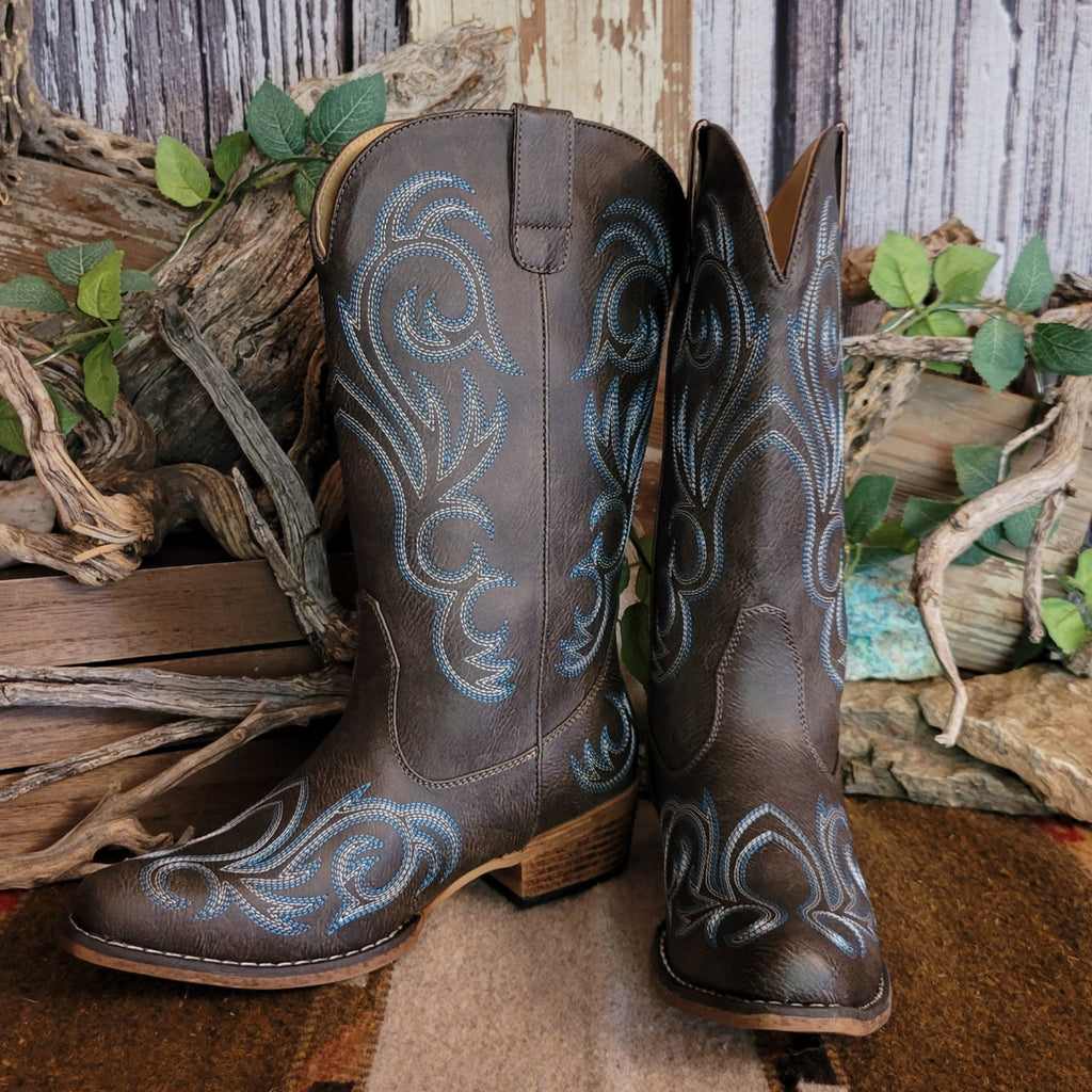 Dark brown faux leather snip toe boot with blue and white stitching along the shaft and toe.