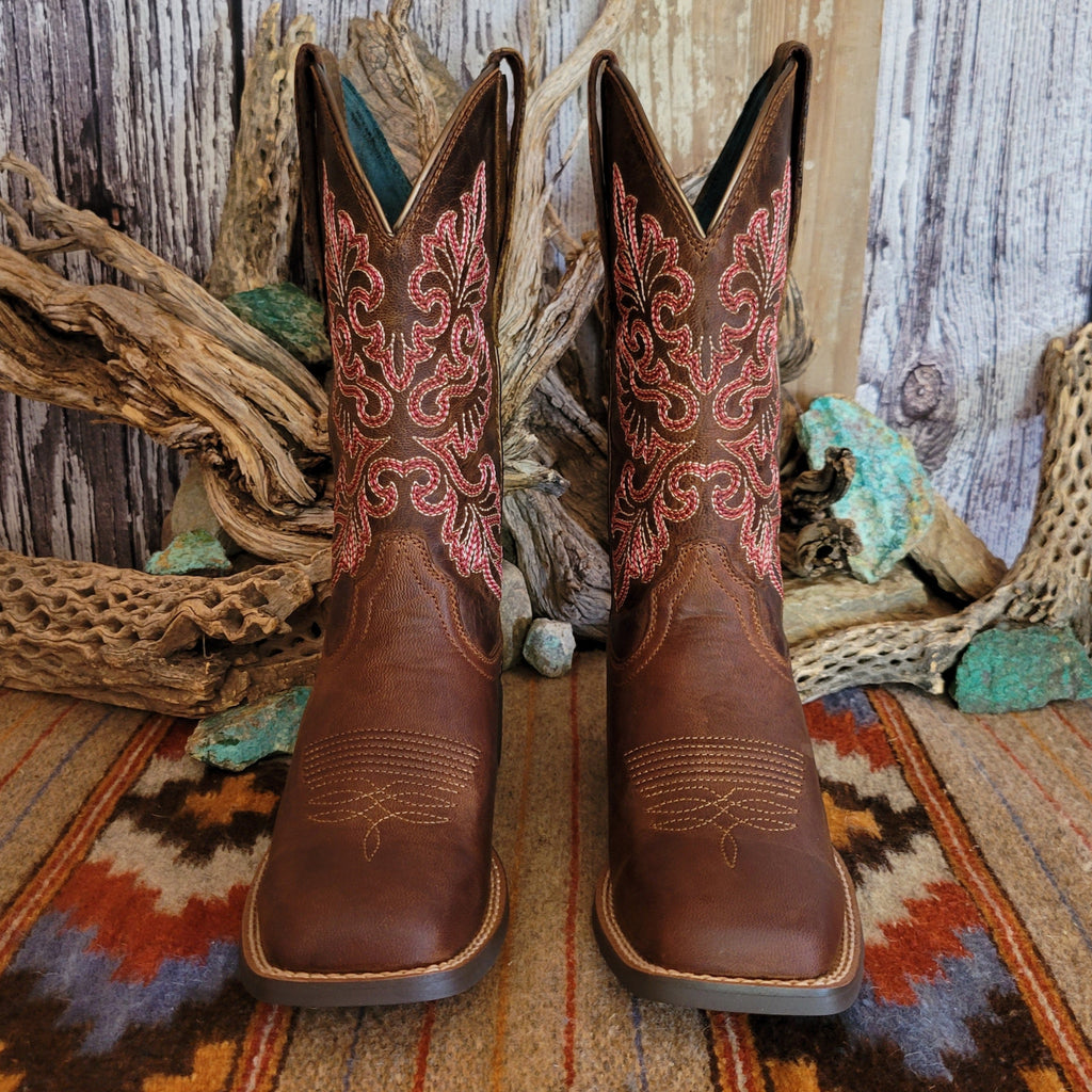 Pair of brown cowgirl boots with intricate red floral stitching.
