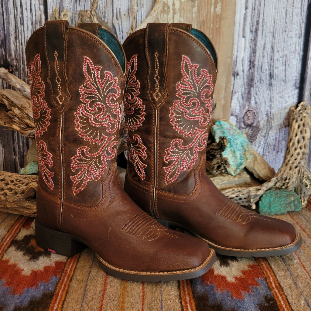 Pair of brown cowgirl boots with intricate red floral stitching.