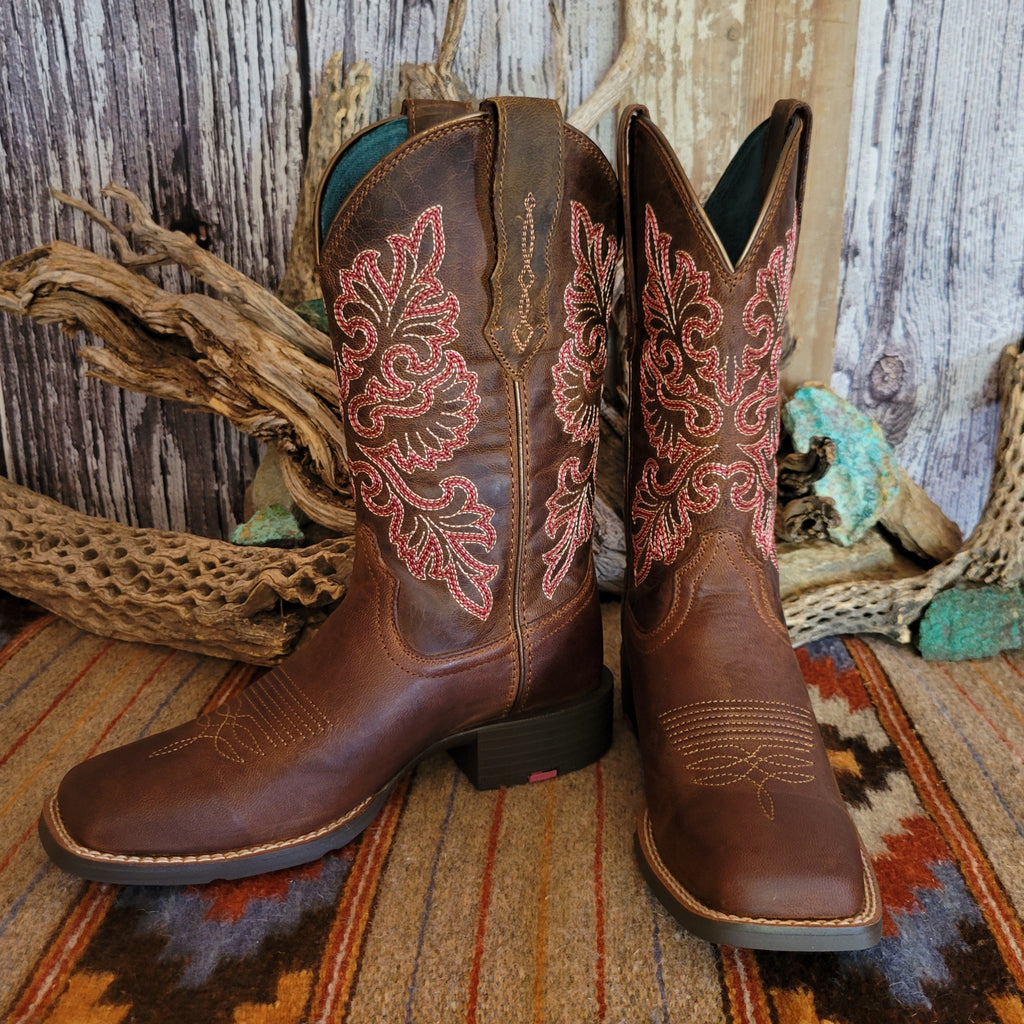 Pair of brown cowgirl boots with intricate red floral stitching.