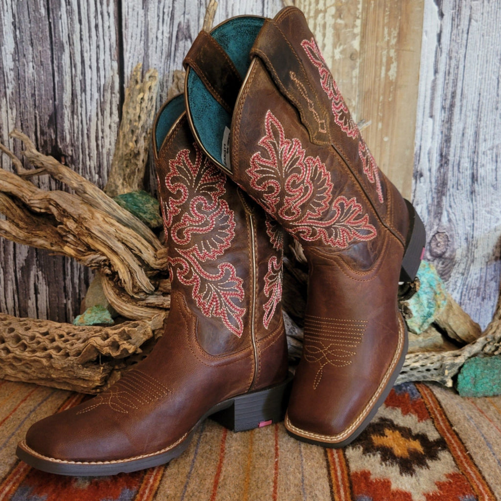 Pair of brown cowgirl boots with intricate red floral stitching.