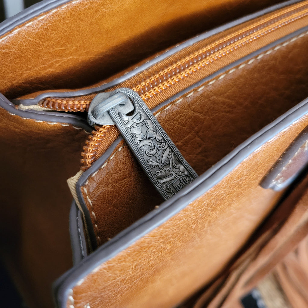 Close up of silver zipper with etched detailing and zipper pocket.