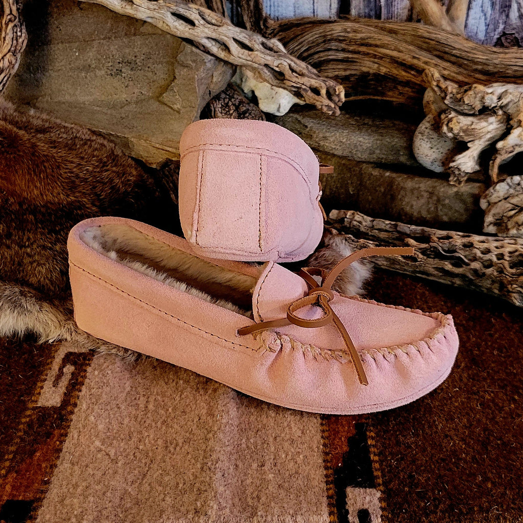 Pair of pink moccasins with pile lined interior, rawhide lace, and soft sole exterior.