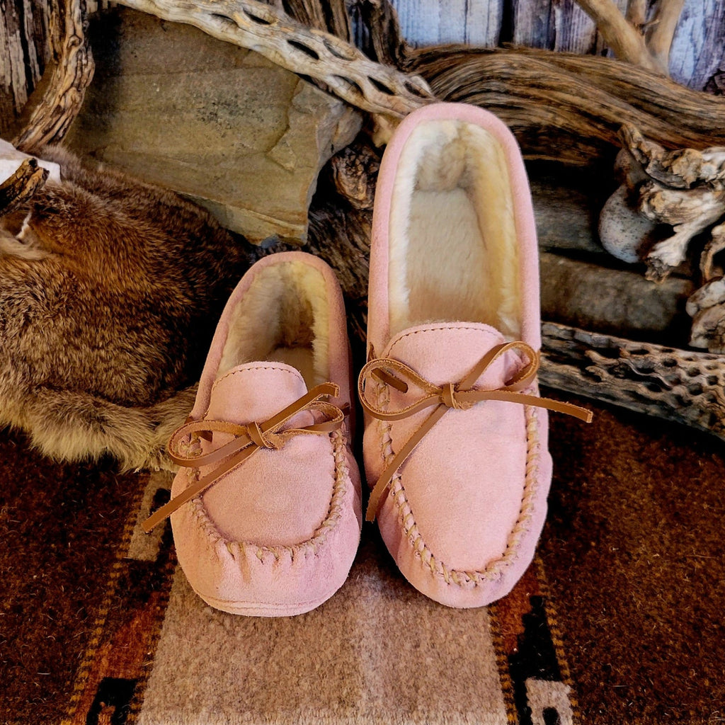 Pair of pink moccasins with pile lined interior, rawhide lace, and soft sole exterior.