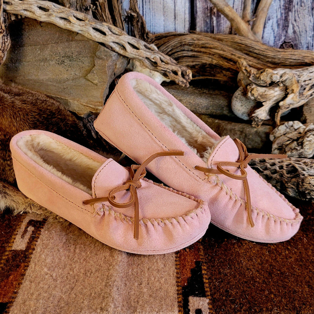 Pair of pink moccasins with pile lined interior, rawhide lace, and soft sole exterior.